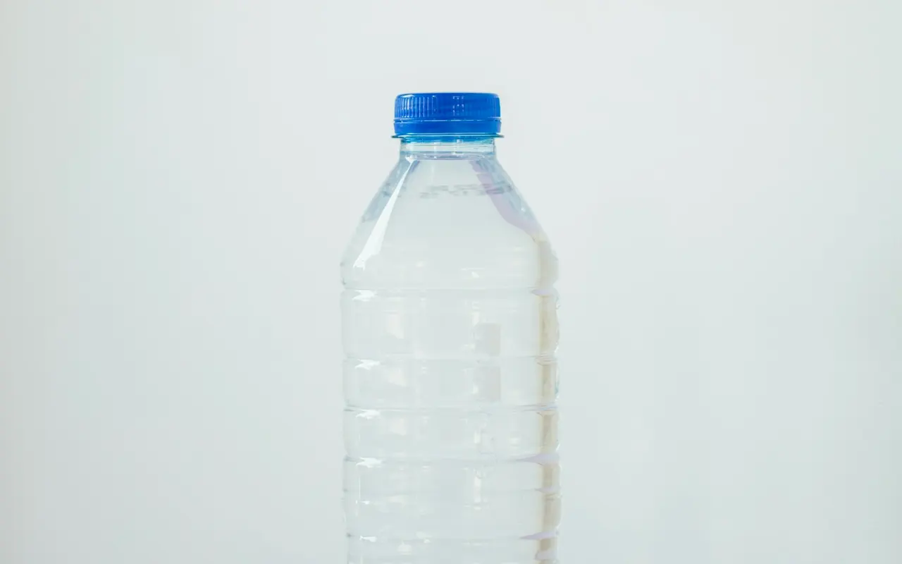 A clear capped water bottle with a blue cap