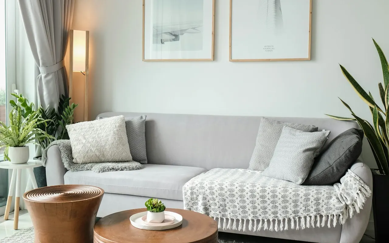 A sofa with cushions and a blanket beside a living-room window