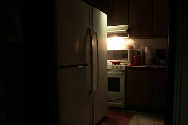 A refrigerator in a dim kitchen at night