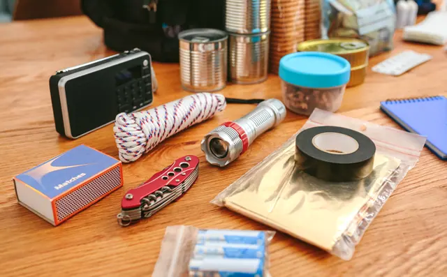A radio, flashlight, batteries and rope laid out on a table