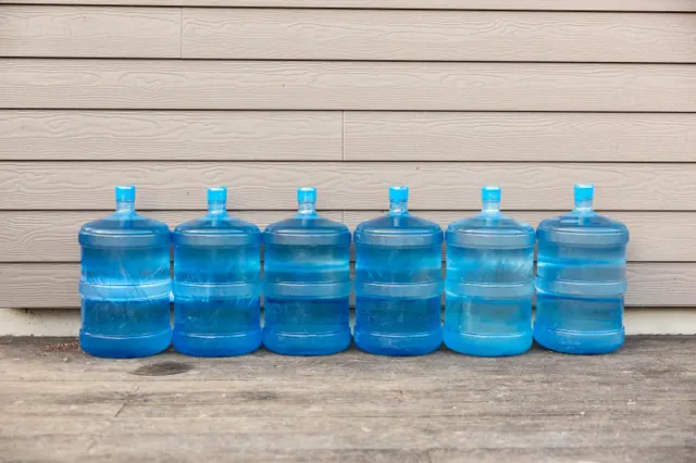 A row of filled blue water jugs